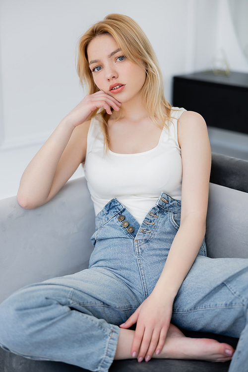 Pretty woman in bodysuit and jeans posing on couch