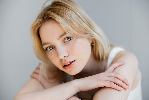 Portrait of young blonde woman looking at camera isolated on grey