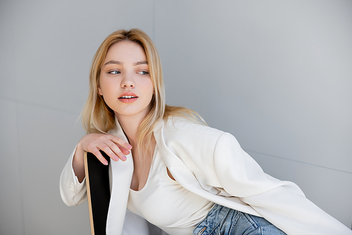 Young woman in jacket looking away while sitting on chair