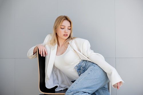 Stylish young woman jacket sitting on chair at home