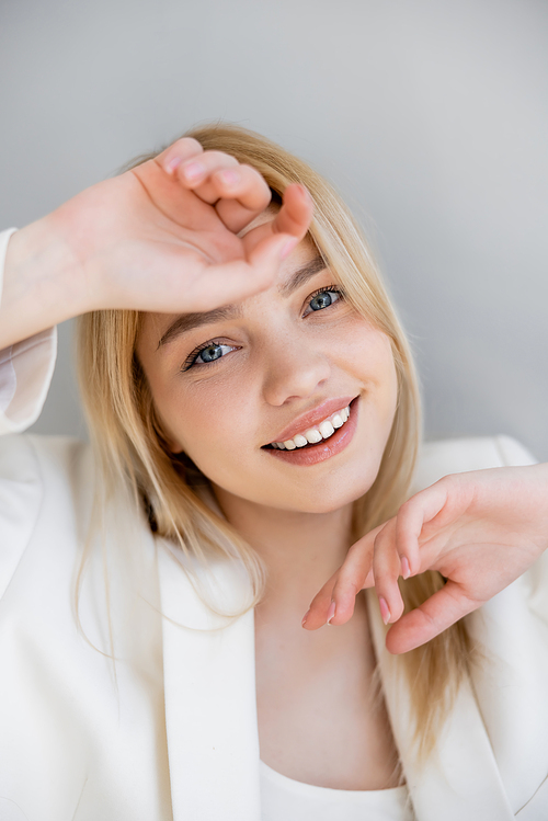 Positive young woman in jacket looking at camera isolated on grey