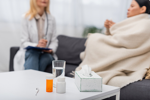 pills and glass of  near blurred woman and doctor at home