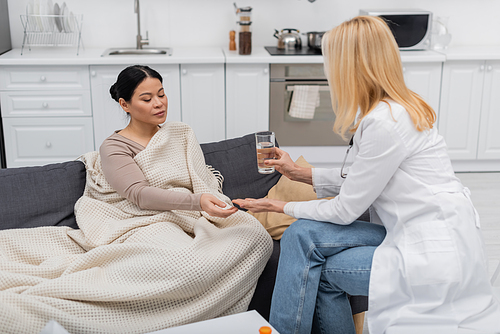 doctor holding glass of  near asian patient at home