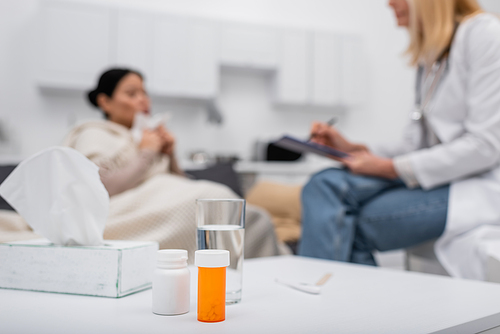 pills and glass of  near blurred doctor and patient at home