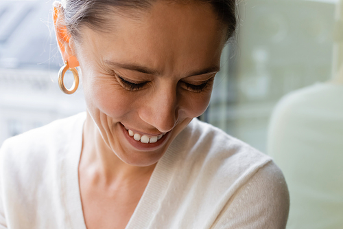 close up portrait of woman in ring earring smiling at home on blurred background