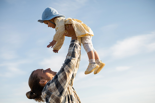Side view of young father holding toddler daughter with sky at background