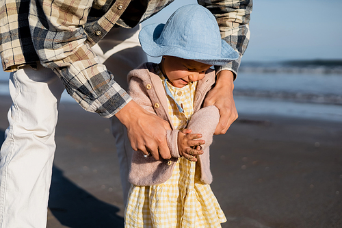 Dad holding cheerful baby daughter on beach