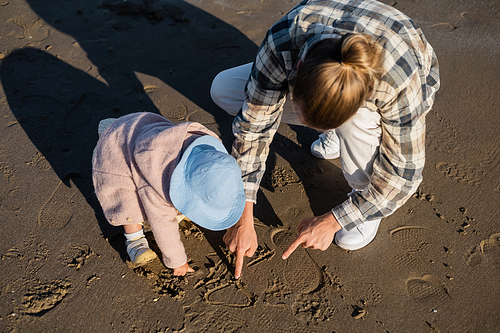 Overhead view of man and baby girl drawing on beach