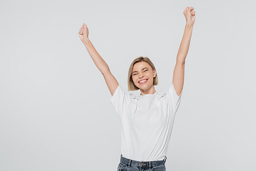 Excited blonde woman in white t-shirt showing yes gesture isolated on grey