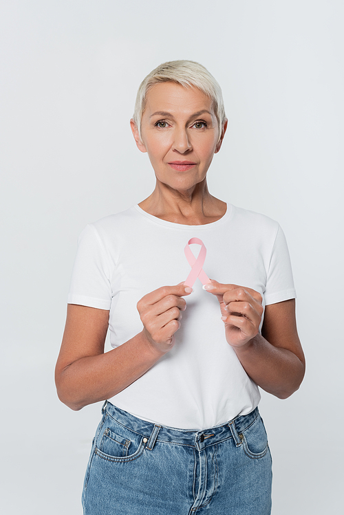 Elderly woman holding ribbon of breast cancer awareness isolated on grey
