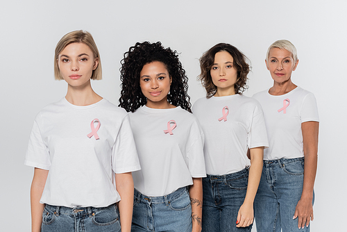 Multiethnic women with ribbons of breast cancer awareness standing isolated on grey