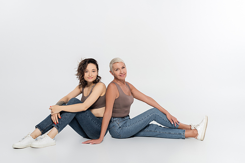 Smiling women sitting on grey background, feminism concept