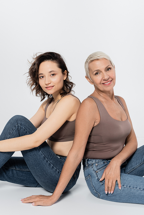 Women smiling at camera while sitting on grey background
