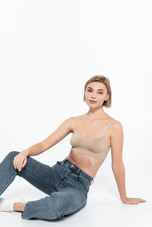 Young blonde woman in jeans posing on grey background