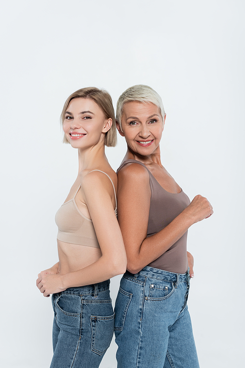 Smiling women standing back to back isolated on grey, feminism concept