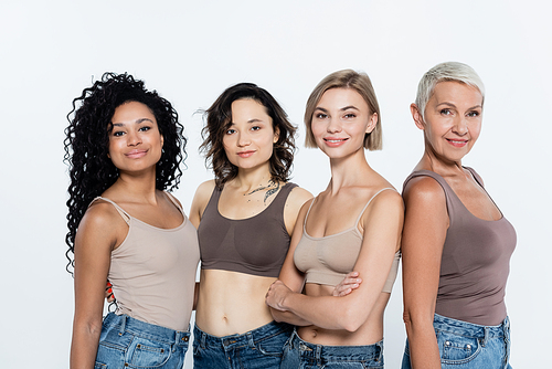 Positive interracial women in tops looking at camera isolated on grey, feminism concept