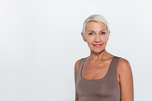 Portrait of cheerful grey haired woman looking at camera isolated on grey