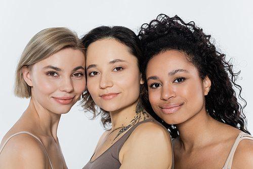 Young interracial women looking at camera isolated on grey
