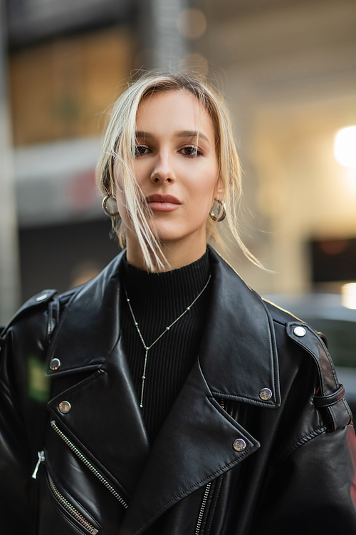 portrait of blonde woman in stylish leather jacket looking at camera
