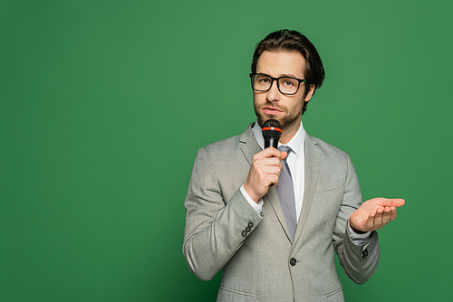 Brunette newscaster in eyeglasses talking at microphone on green background