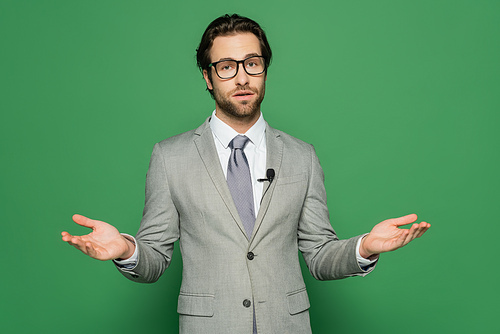 Newscaster in eyeglasses and clip microphone talking on green background