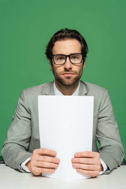 broadcaster in eyeglasses and grey suit holding blank paper isolated on green