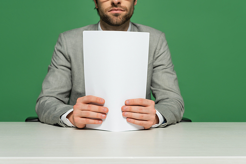 cropped view of broadcaster in grey suit holding blank paper isolated on green