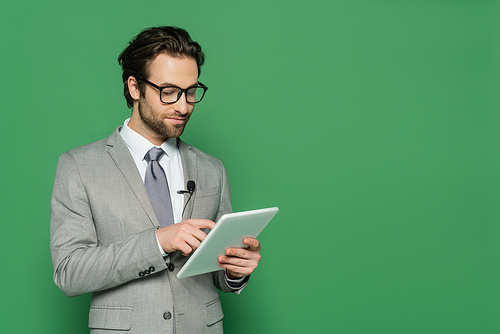 journalist in eyeglasses and suit using digital tablet isolated on green