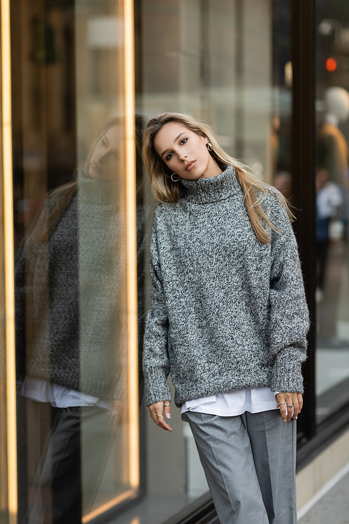 young woman in grey outfit leaning on window display in New York