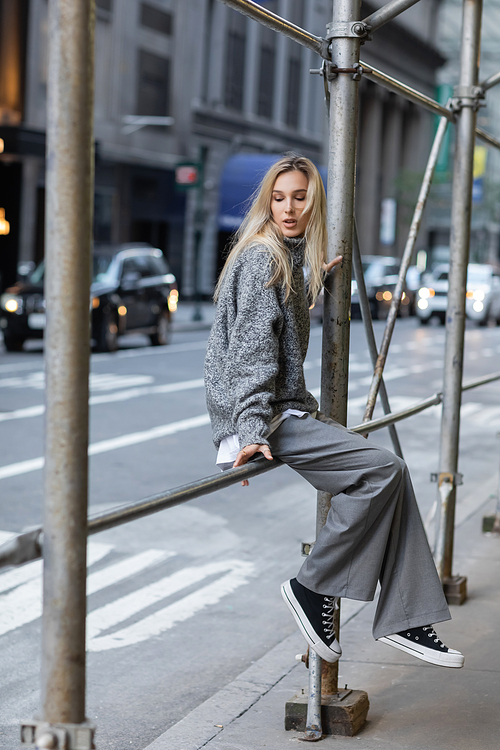 full length of stylish woman in grey winter outfit posing on urban street in New York city