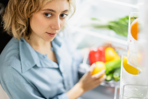 high angle view of young woman standing near opened refrigerator