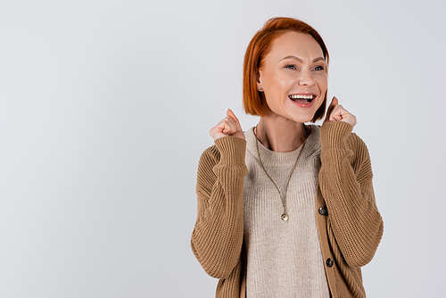 Cheerful red haired woman showing yes gesture isolated on grey