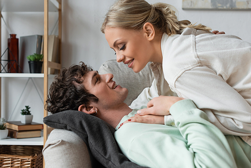 side view of happy young couple lying on couch in living room