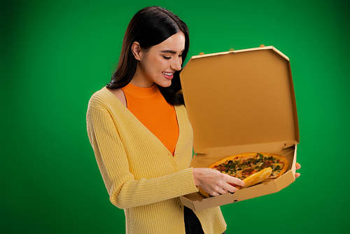 happy young woman holding carton box with delicious pizza isolated on green