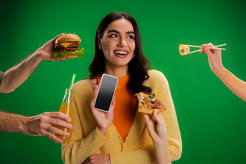 happy woman holding smartphone with blank screen near people with assortment of food isolated on green