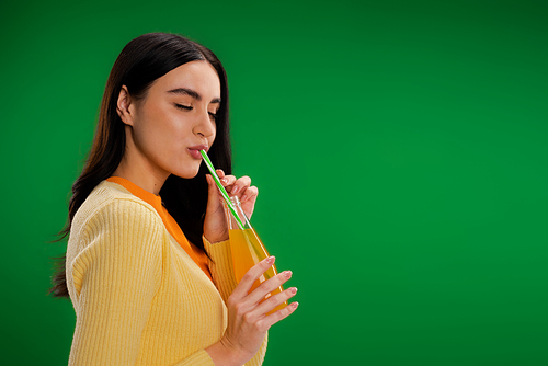 brunette woman with closed eyes enjoying fresh lemonade isolated on green
