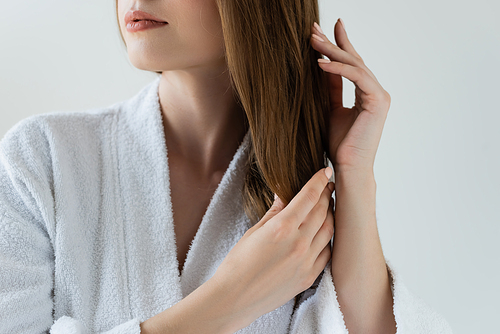 cropped view of young woman touching shiny and healthy hair isolated on grey