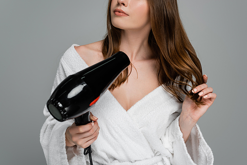 cropped view of young woman with shiny hair using hair dryer isolated on grey