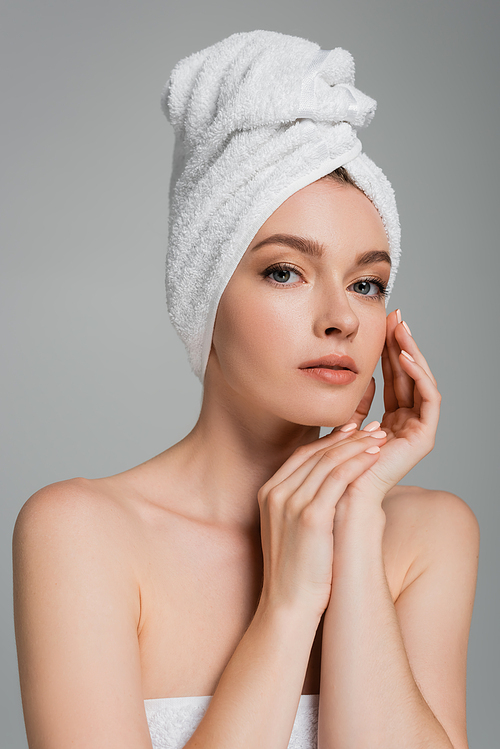 young woman with bare shoulders and towel on head looking at camera isolated on grey