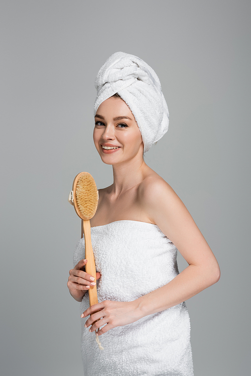 happy young woman with towel on head holding wooden hair brush isolated on grey