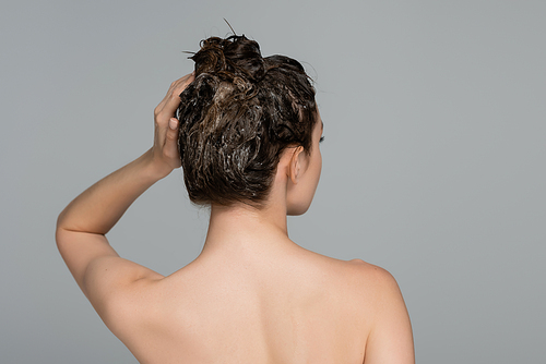 back view of woman with bare shoulders washing hair isolated on grey