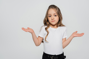 confused girl showing shrug gesture while looking at camera isolated on grey