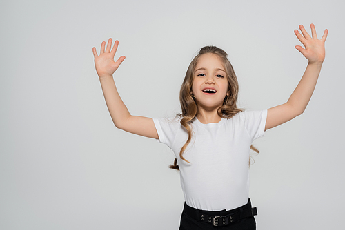 excited girl in white t-shirt waving hands while looking at camera isolated on grey