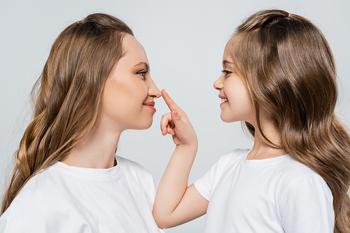 side view of happy girl touching nose of smiling mom isolated on grey