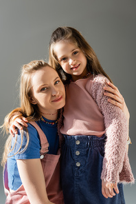 cheerful mother and daughter hugging isolated on grey