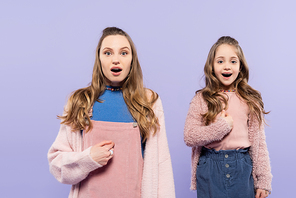 amazed mother and daughter pointing at themselves isolated on purple
