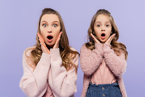 shocked mother and daughter looking at camera isolated on purple