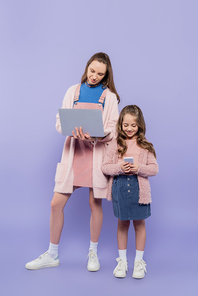 full length of mother and child using gadgets on purple