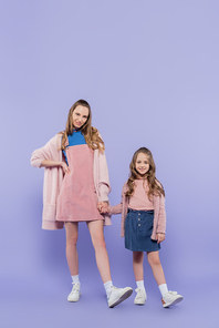 full length of happy kid and mother holding hands on purple