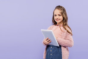 joyful child using digital tablet isolated on purple
